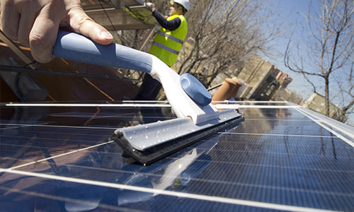 a man uses a squeegee to clean a solar panel