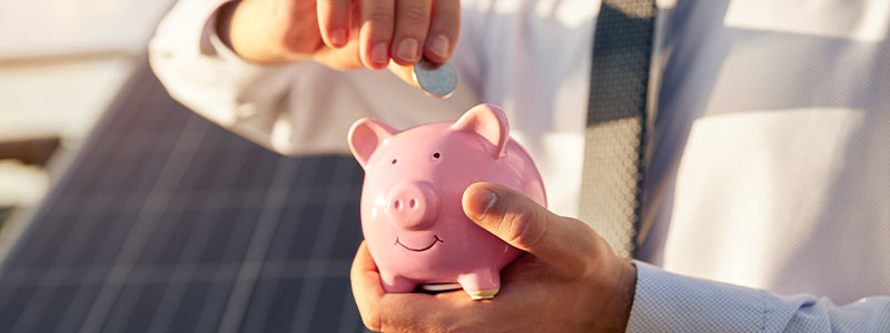 a man in a white shirt and silver tie puts a quarter in a pink piggy bank