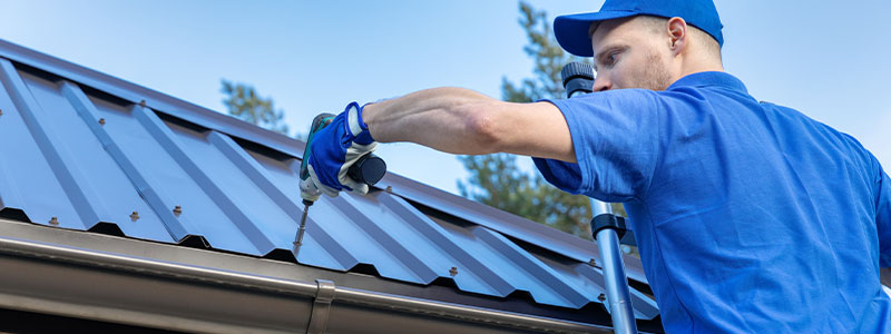 a professional roofer in a blue uniform installing a metal roof